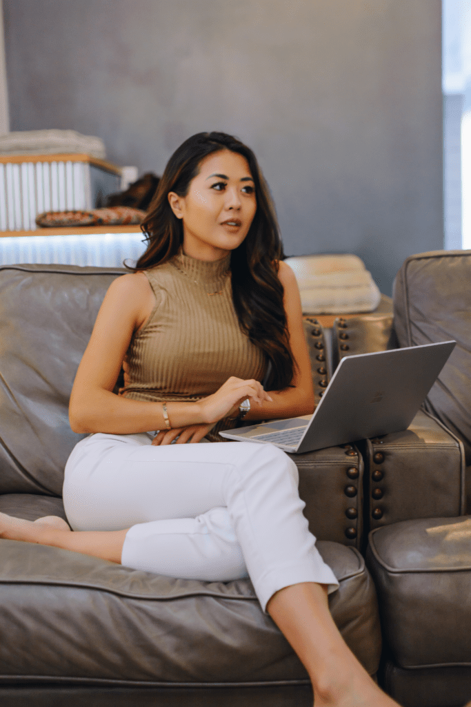 Demi Bang sitting on a couch with a Microsoft Surface Pro laptop.