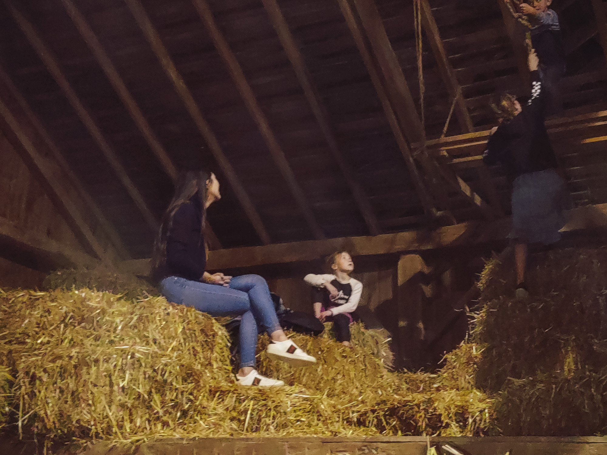 Lifestyle blogger Demi Bang sits on top of a bale in a barn.